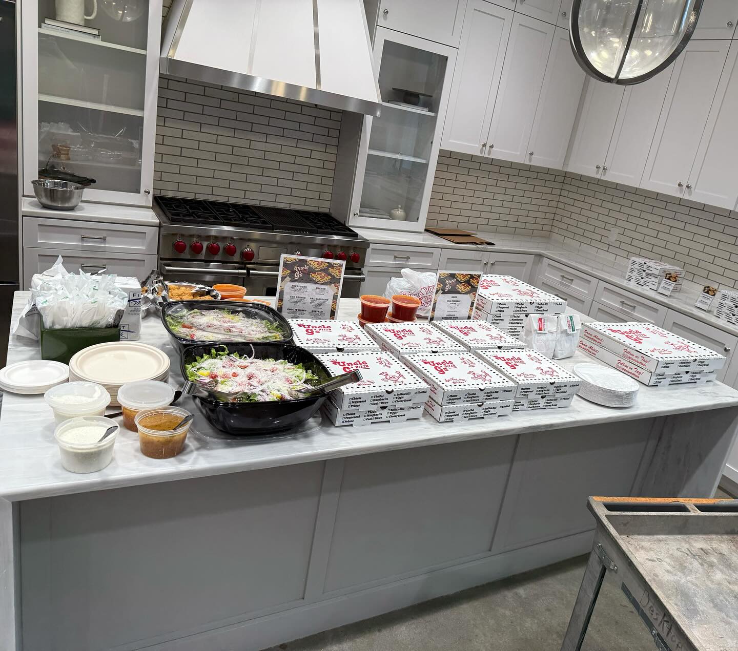 Uncle G's catering spread with pizza boxes and salads