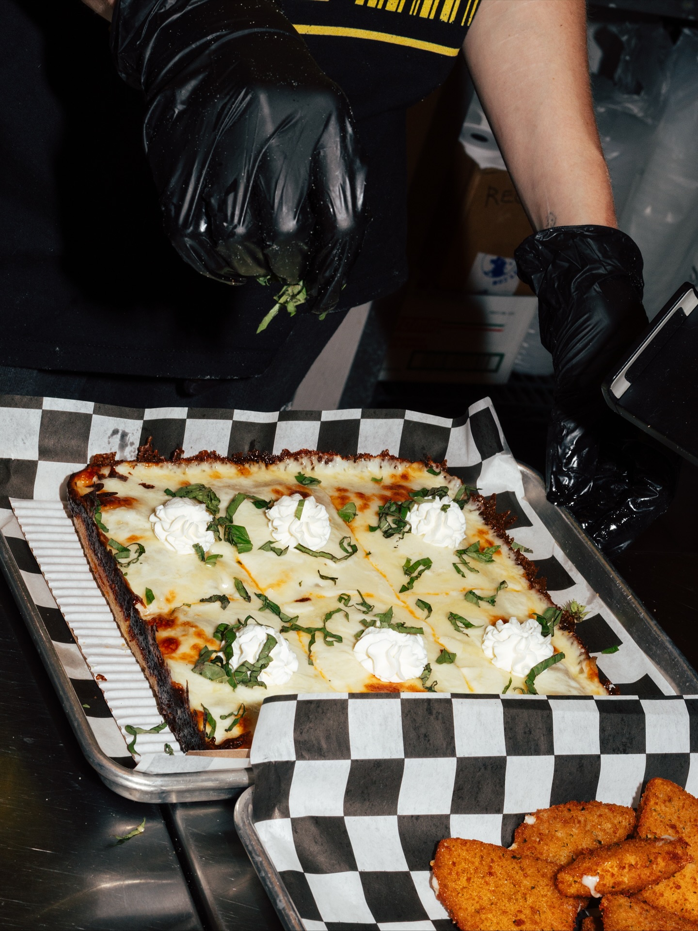 Uncle G's team finishing a Detroit-style pan in the kitchen